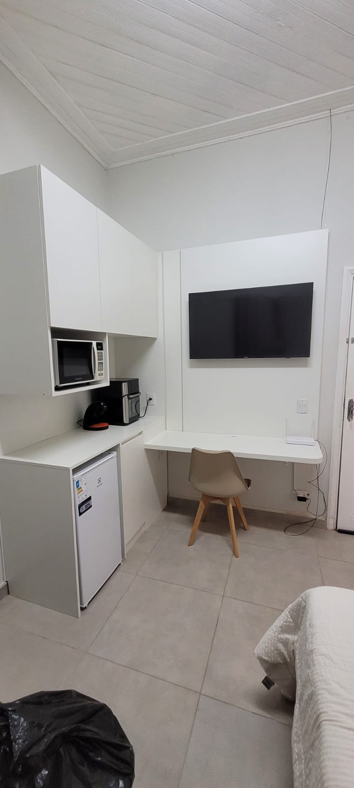 Kitchenette compacta com armários brancos e frigobar