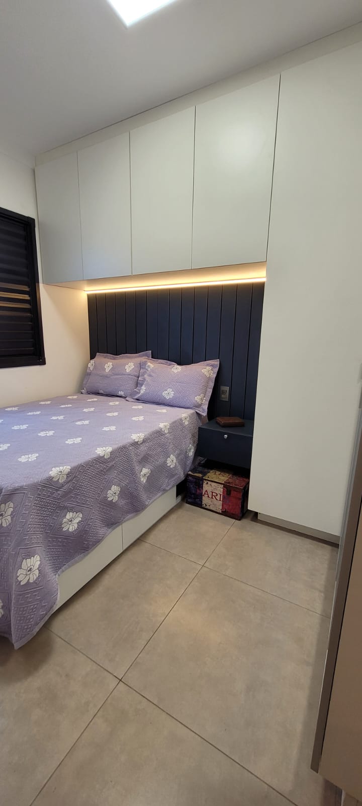 Quarto com armários brancos sobre a cama e cabeceira azul